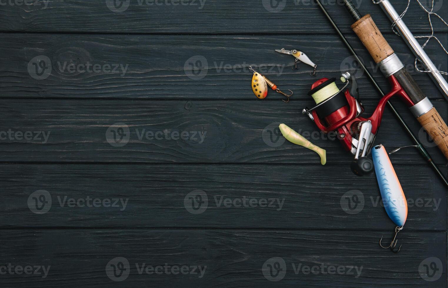 Fishing tackle - fishing spinning, hooks and lures on darken wooden background. Top view photo