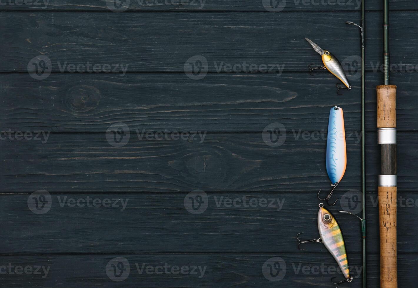 Fishing tackle - fishing spinning, hooks and lures on darken wooden background. Top view photo