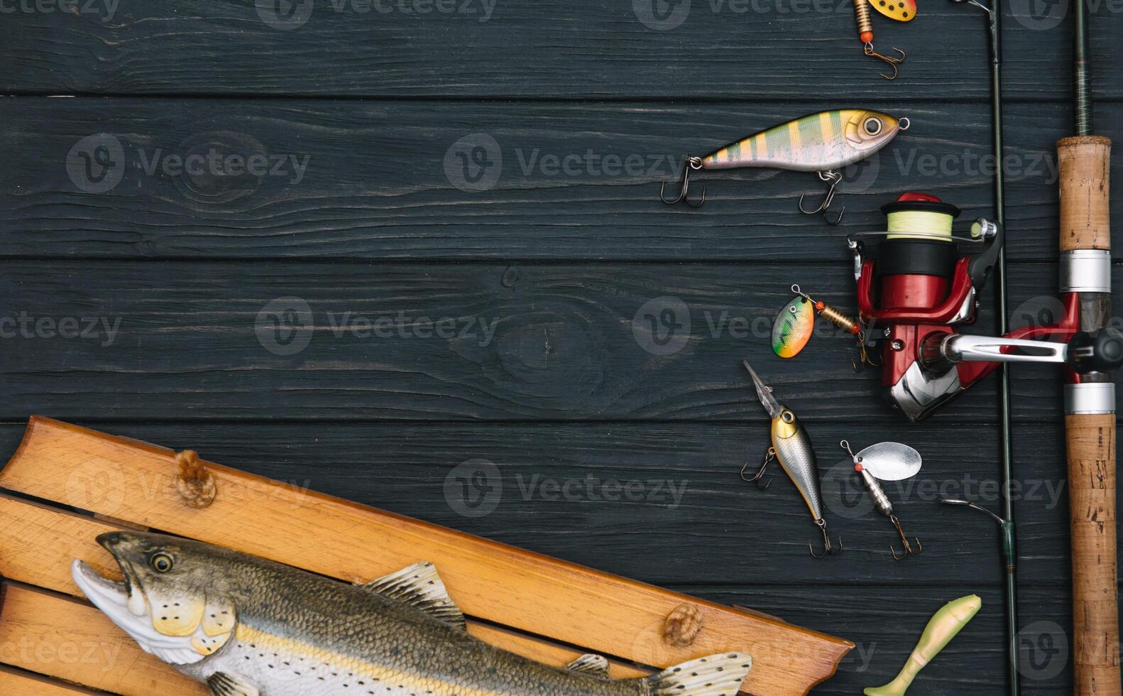 Fishing tackle - fishing spinning, hooks and lures on darken wooden background. Top view photo