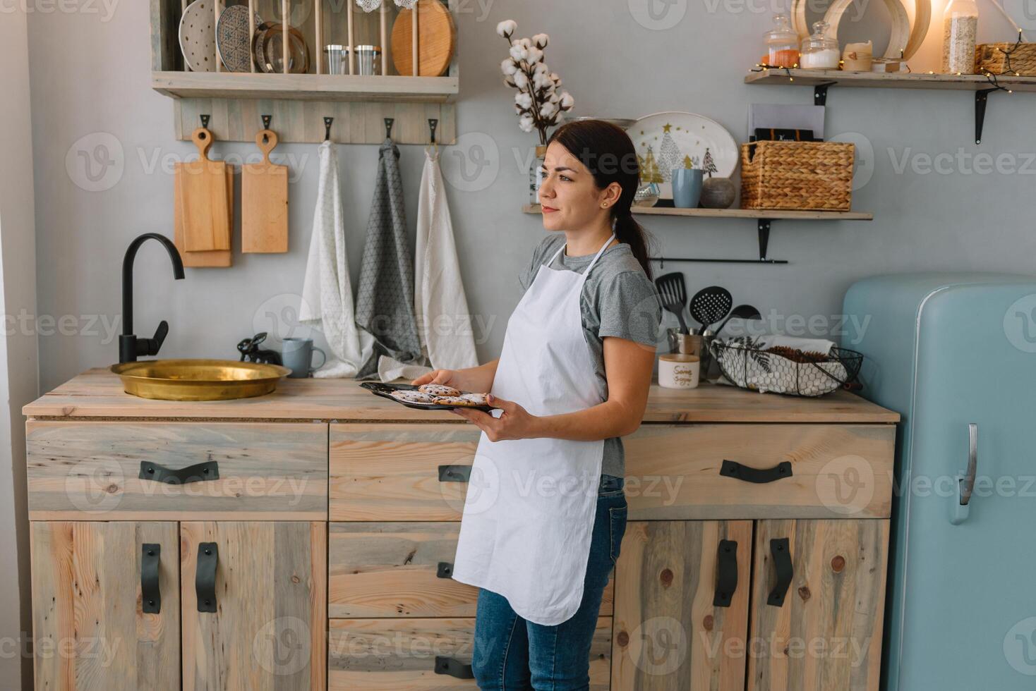 joven contento mamá y su bebé cocinar galletas a hogar en el cocina. Navidad hecho en casa pan de jengibre. linda chico con madre en blanco uniforme y sombrero cocido chocolate galletas foto