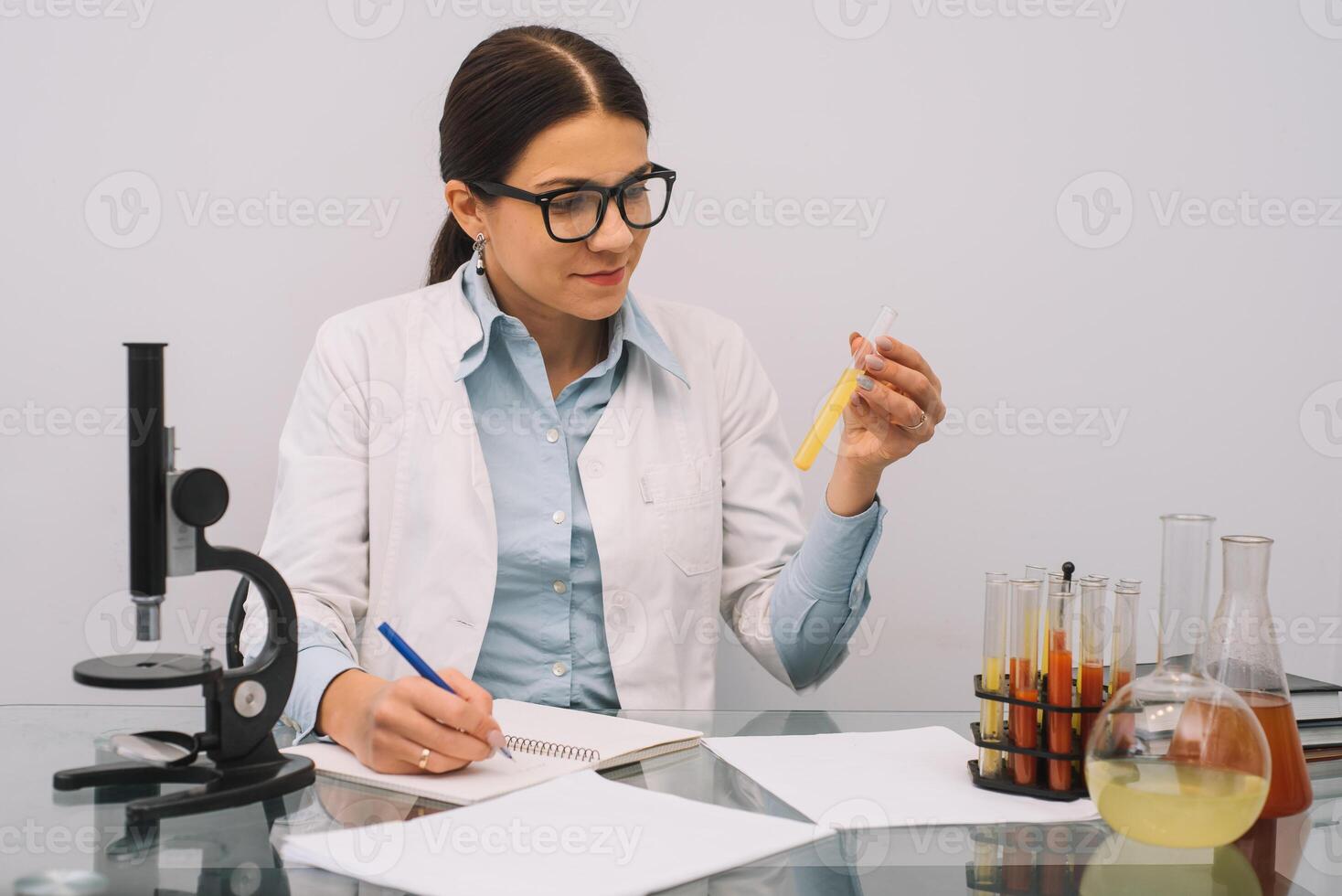 Beautiful medical doctors in gloves and glasses are working with substances in test tubes and microscope at the lab photo