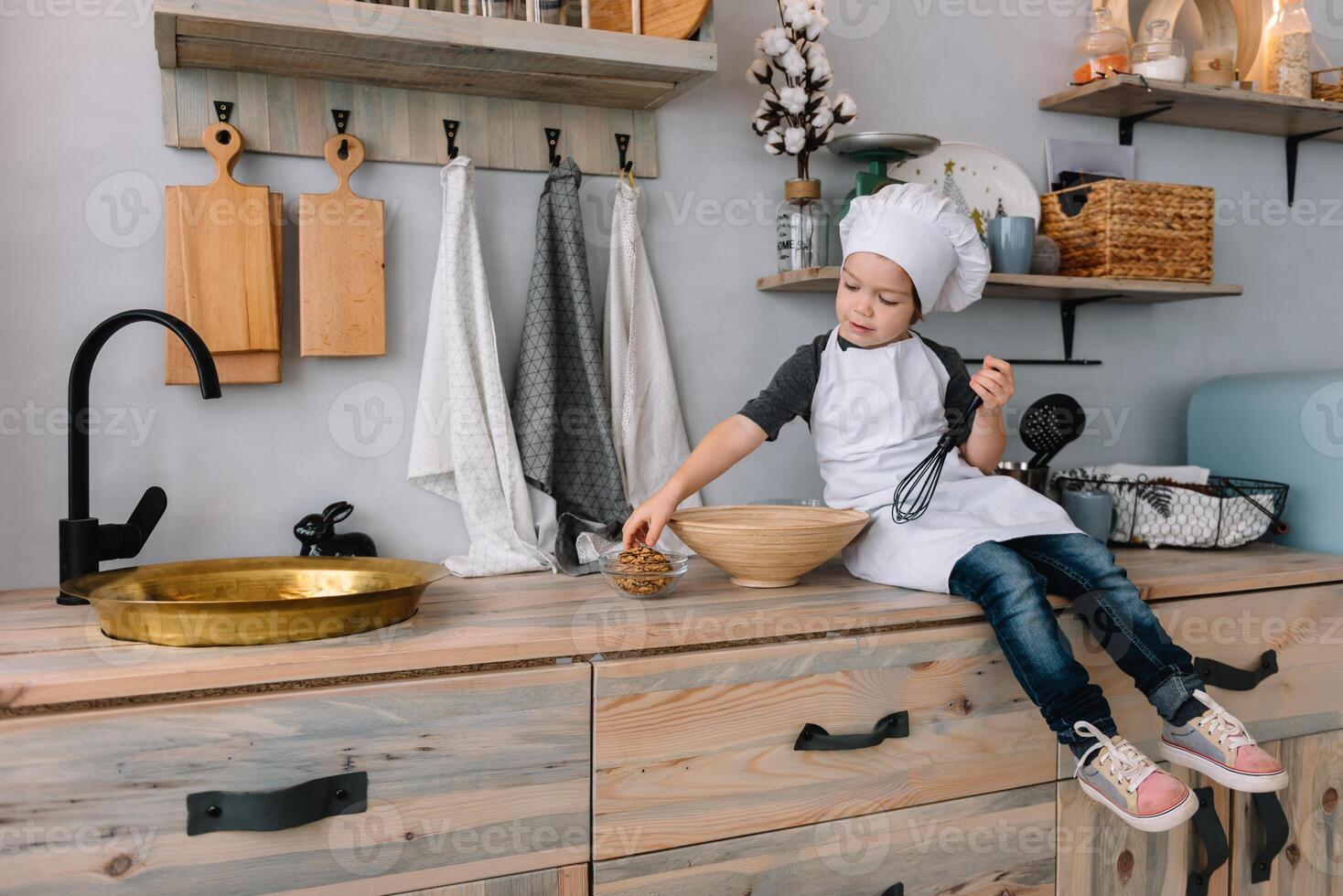 joven contento mamá y su bebé cocinar galletas a hogar en el cocina. Navidad hecho en casa pan de jengibre. linda chico con madre en blanco uniforme y sombrero cocido chocolate galletas. foto