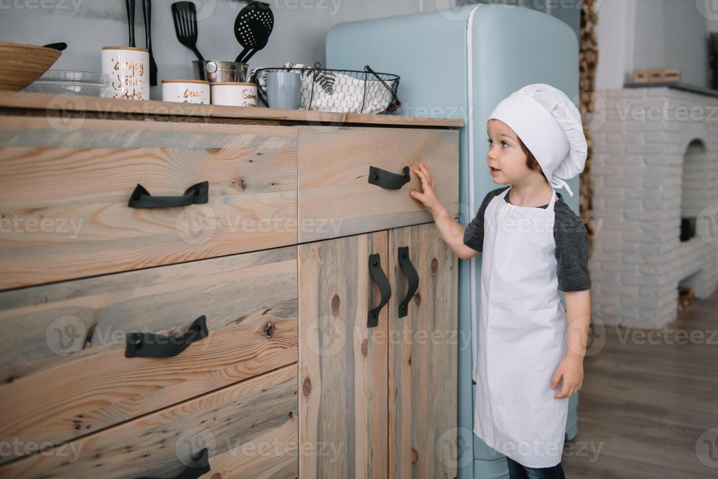 Young boy cute on the kitchen cook chef in white uniform and hat near table. Christmas homemade gingerbread. the boy cooked the chocolate cookies. photo