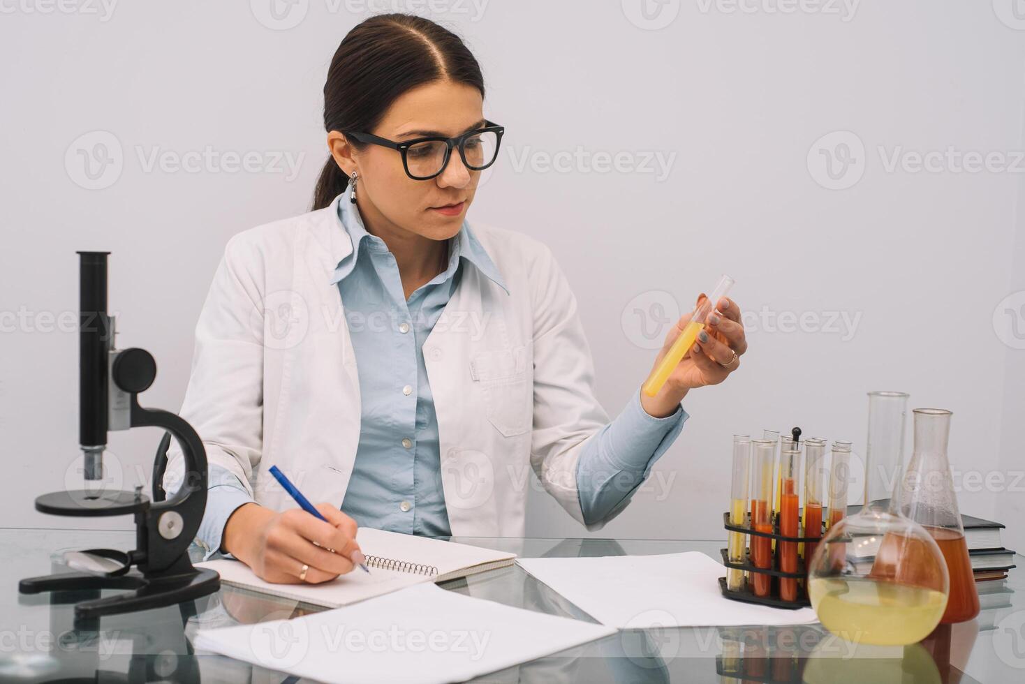 hermosa médico doctores en guantes y lentes son trabajando con sustancias en prueba tubos y microscopio a el laboratorio foto