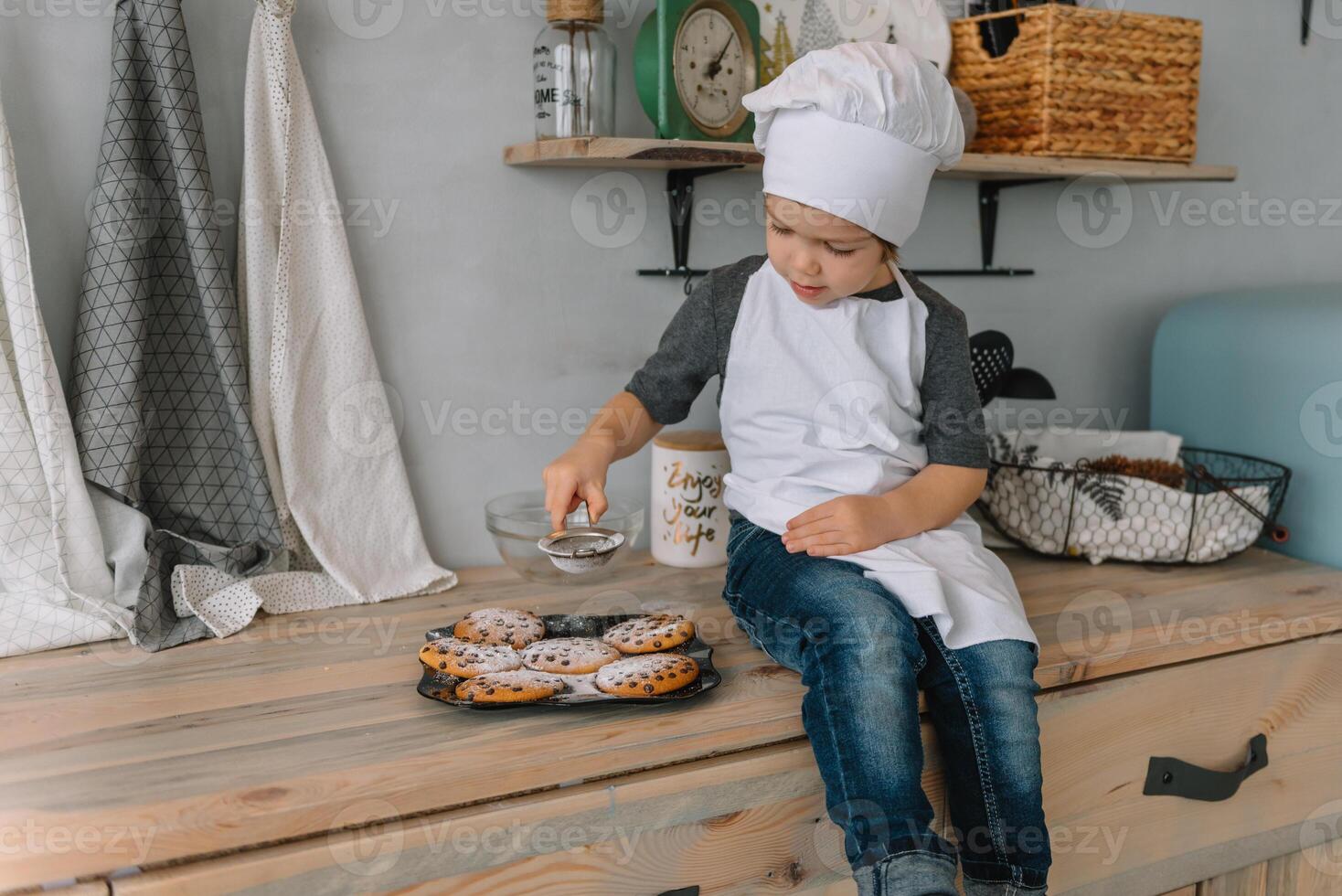 Young happy mom and her baby cook cookies at home in the kitchen. Christmas Homemade Gingerbread. cute boy with mother in white uniform and hat cooked chocolate cookies photo