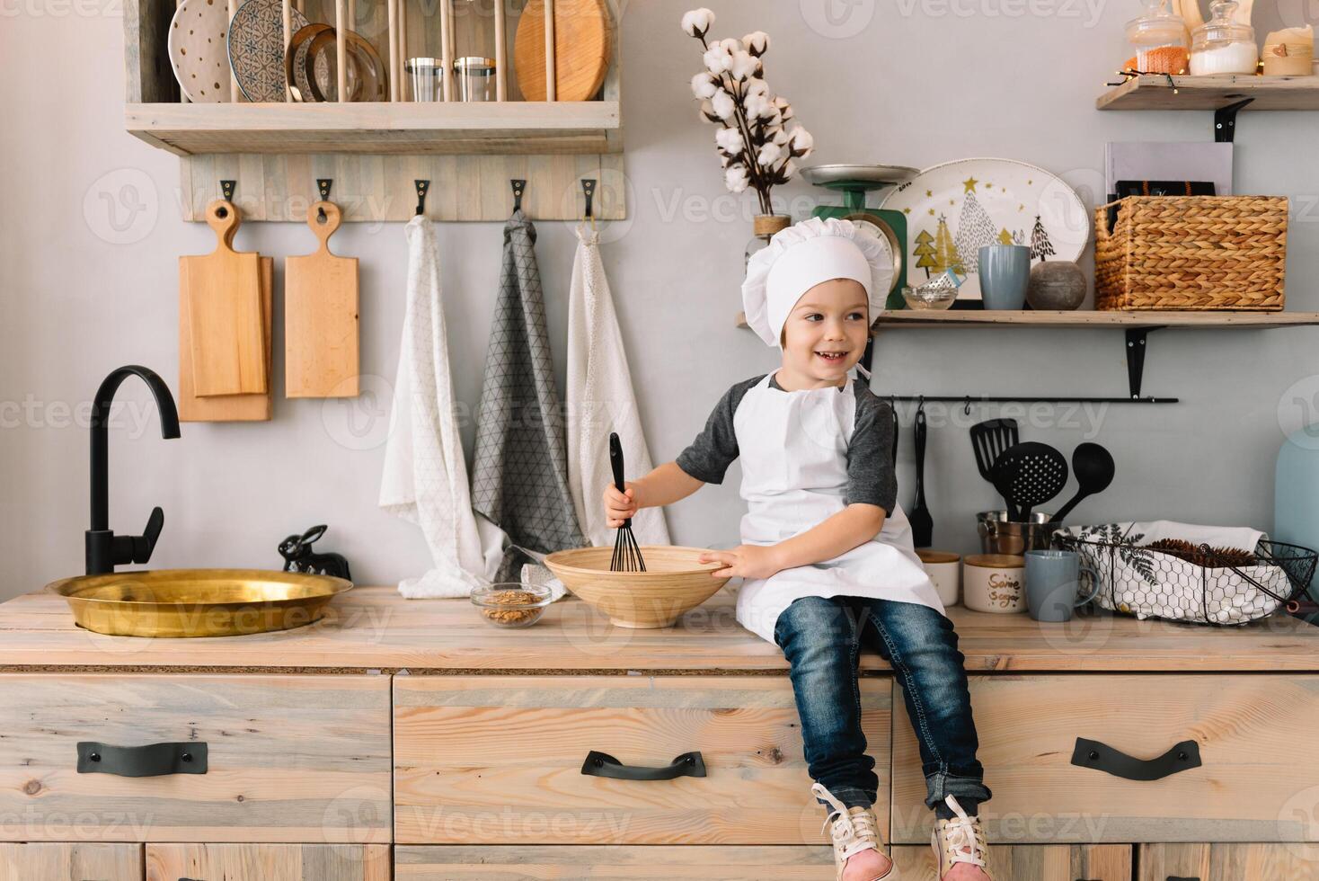 Young boy cute on the kitchen cook chef in white uniform and hat near table. Christmas homemade gingerbread. the boy cooked the chocolate cookies. photo