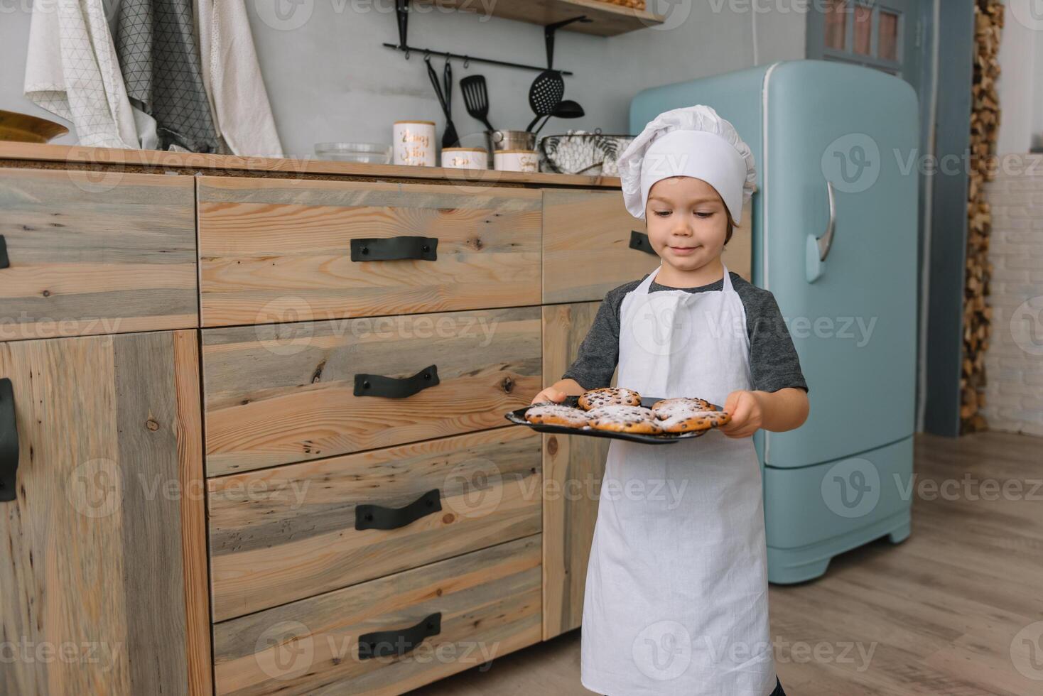 Young boy cute on the kitchen cook chef in white uniform and hat near table. Christmas homemade gingerbread. the boy cooked the chocolate cookies photo