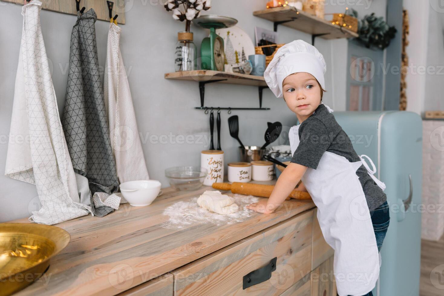 Young happy mom and her baby cook cookies at home in the kitchen. Christmas Homemade Gingerbread. cute boy with mother in white uniform and hat cooked chocolate cookies. photo