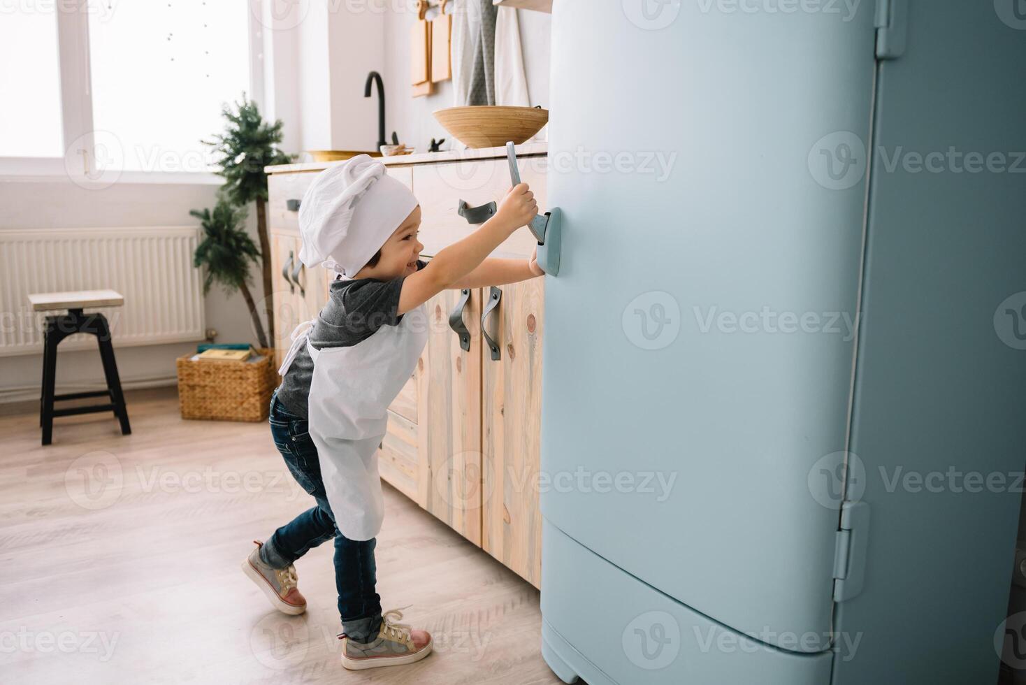 joven contento mamá y su bebé cocinar galletas a hogar en el cocina. Navidad hecho en casa pan de jengibre. linda chico con madre en blanco uniforme y sombrero cocido chocolate galletas. foto