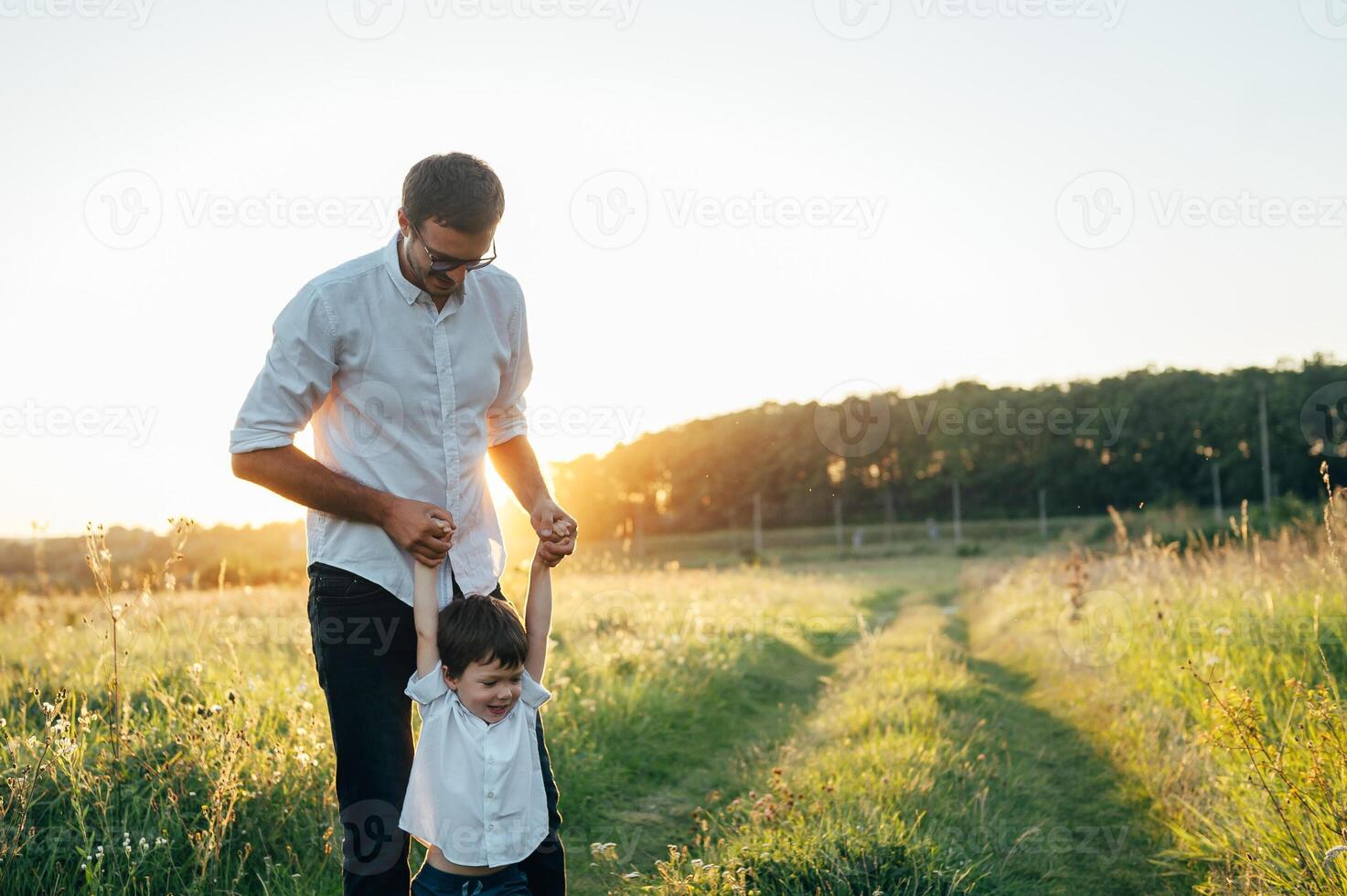 Handsome dad with his little cute son are having fun and playing on green grassy lawn. Happy family concept. Beauty nature scene with family outdoor lifestyle. family resting together. Fathers day. photo