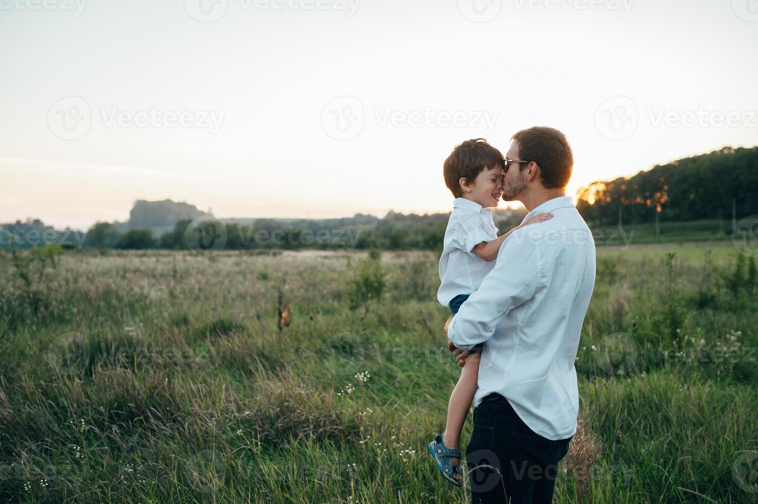 Handsome dad with his little cute son are having fun and playing on green grassy lawn. Happy family concept. Beauty nature scene with family outdoor lifestyle. family resting together. Fathers day. photo