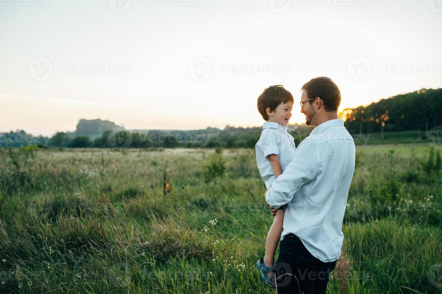 Handsome dad with his little cute son are having fun and playing on green grassy lawn. Happy family concept. Beauty nature scene with family outdoor lifestyle. family resting together. Fathers day. photo