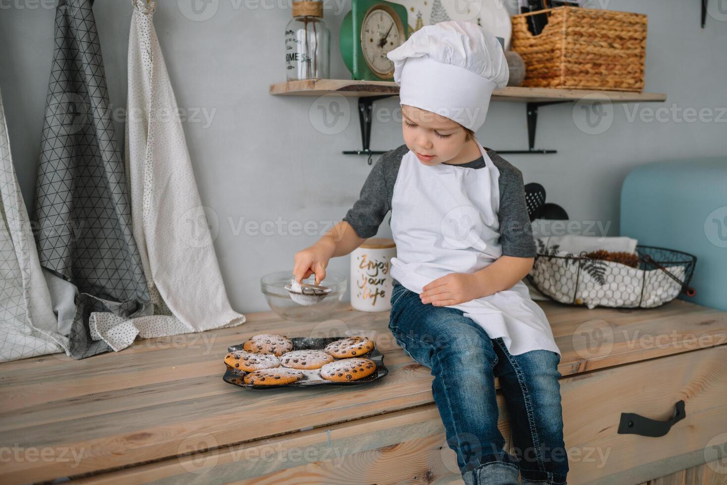 Young happy mom and her baby cook cookies at home in the kitchen. Christmas Homemade Gingerbread. cute boy with mother in white uniform and hat cooked chocolate cookies photo