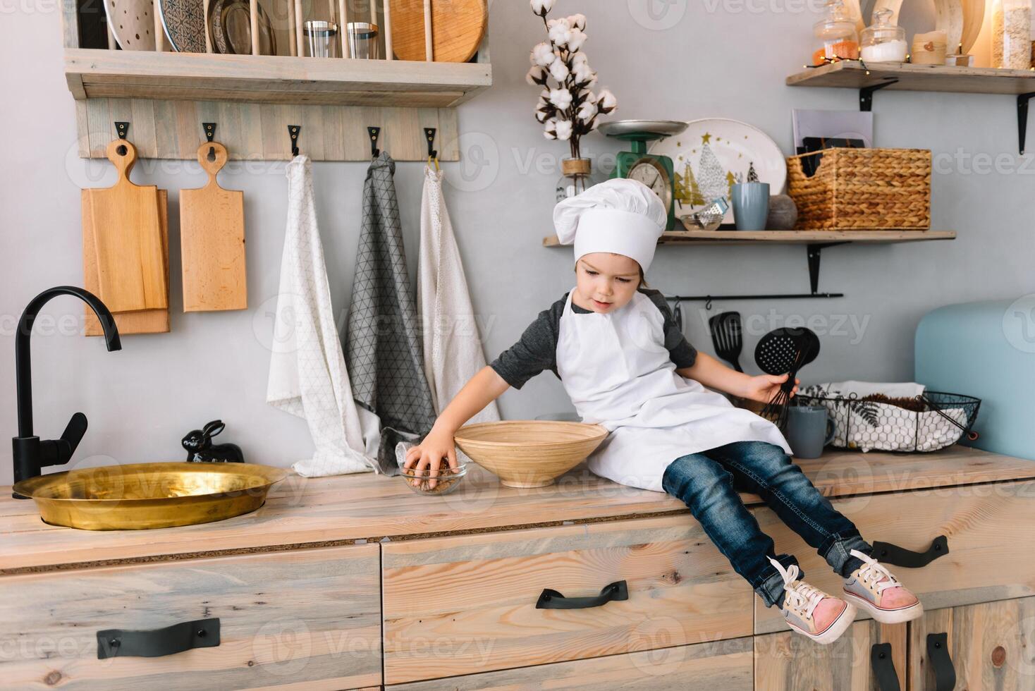 joven contento mamá y su bebé cocinar galletas a hogar en el cocina. Navidad hecho en casa pan de jengibre. linda chico con madre en blanco uniforme y sombrero cocido chocolate galletas. foto