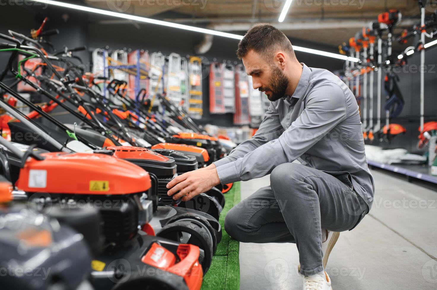 Young man buys a new lawnmower in a garden supplies store photo