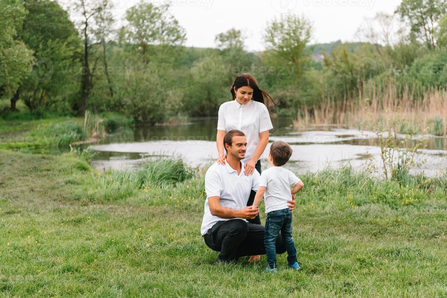 Happy family mother father and child son on nature on sunset. Mom, Dad and kid laughing and hugging, enjoying nature outside. Sunny day, good mood. concept of a happy family. photo