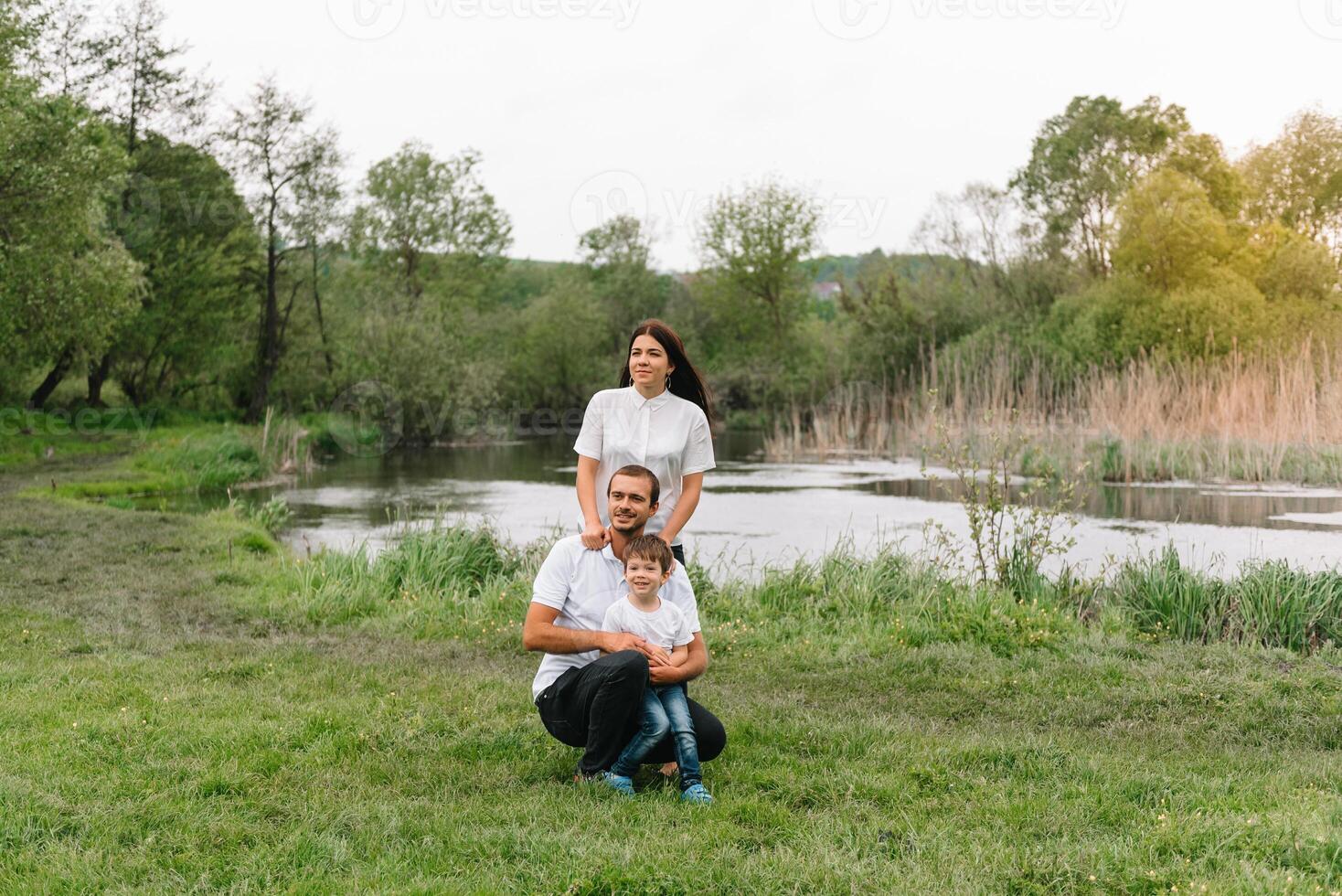 Happy family mother father and child son on nature on sunset. Mom, Dad and kid laughing and hugging, enjoying nature outside. Sunny day, good mood. concept of a happy family. photo