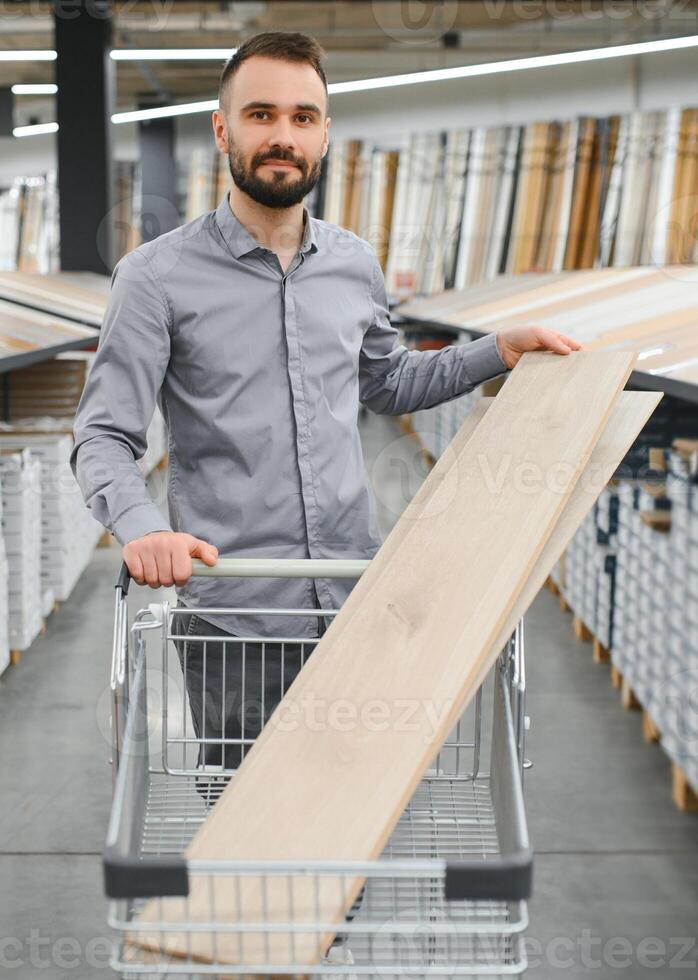 A young man chooses laminate flooring in the hardware store photo