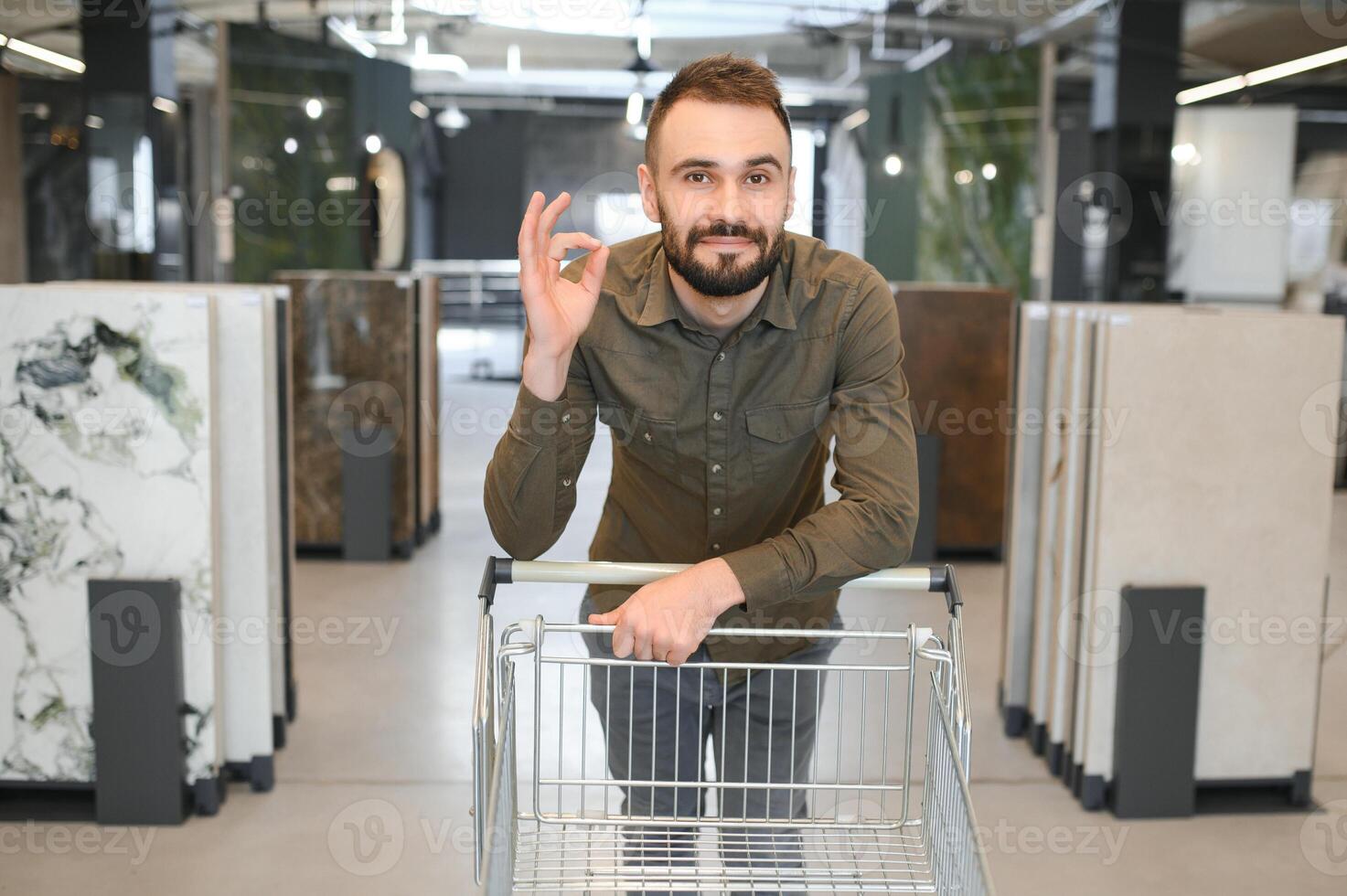 Confident male customer picking out wall tile materials for bathroom in hardware store photo