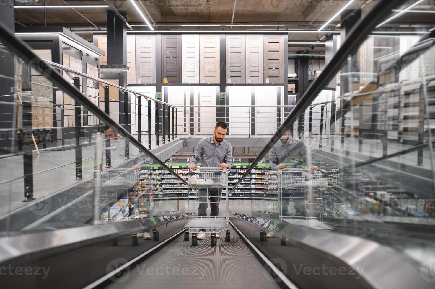 A man with a shopping cart on an escalator in a hardware store. photo