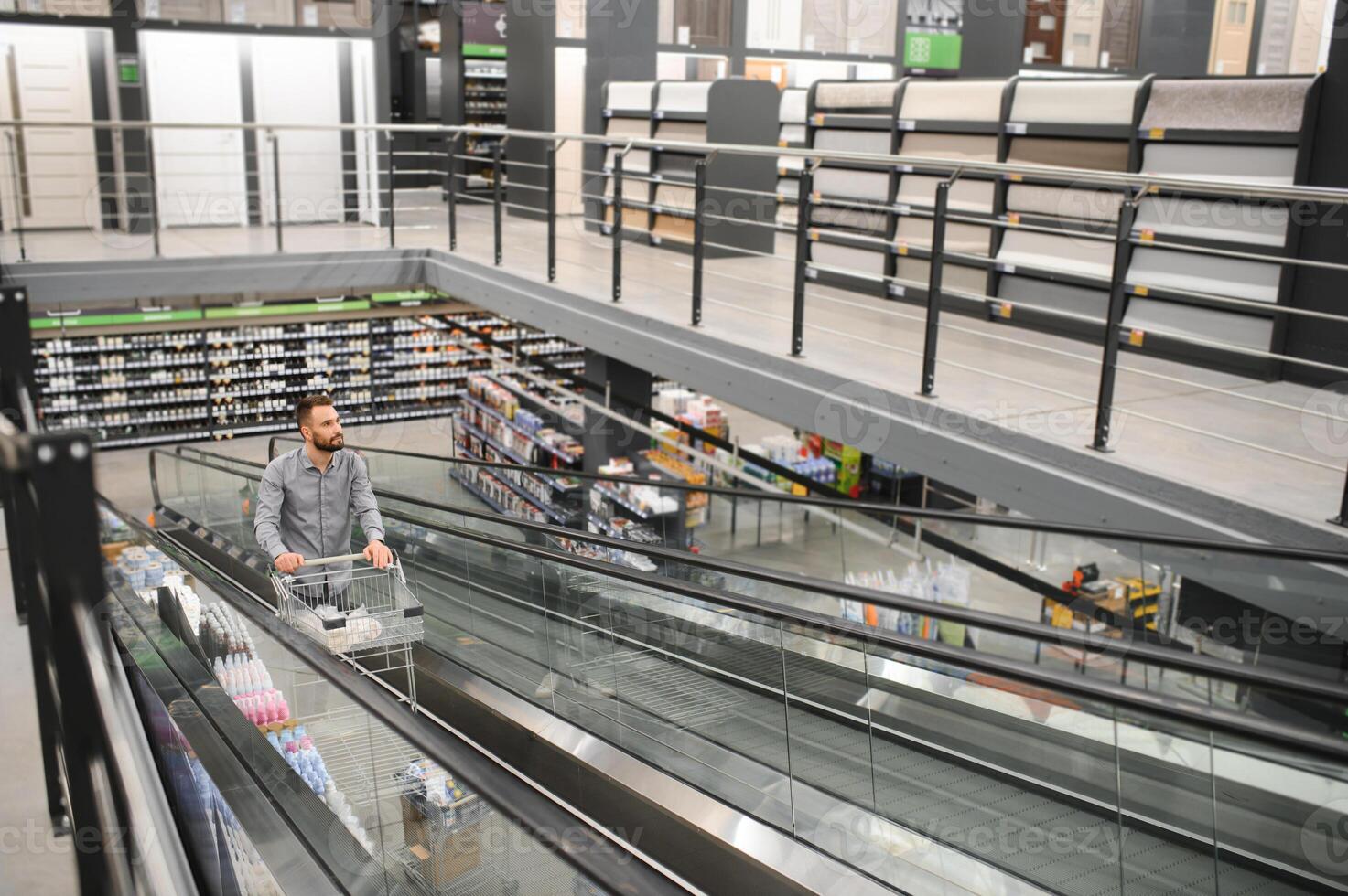 A man with a shopping cart on an escalator in a hardware store. photo