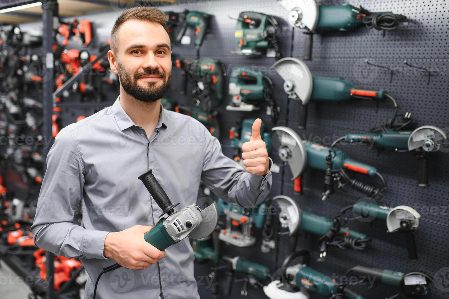 Confident smiling salesman on foreground in power tools store photo