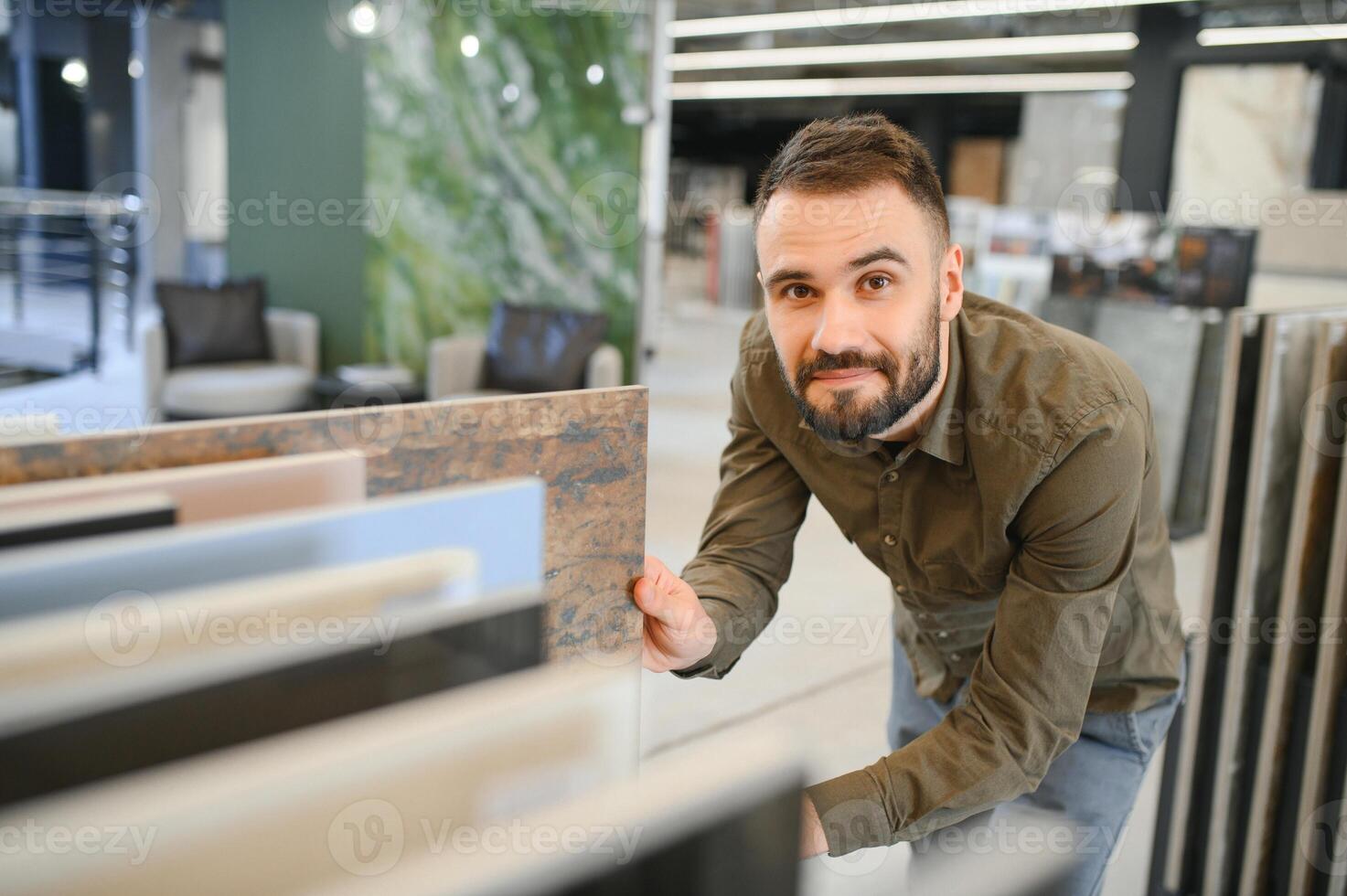 Handsome man customer choosing ceramic tile at building materials store photo