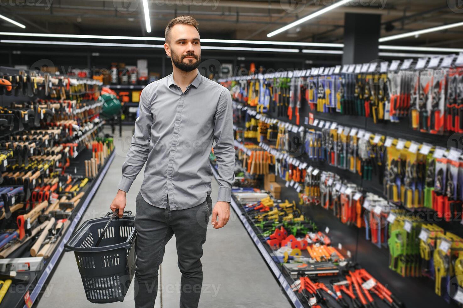 male builder in a hardware store chooses a tools photo