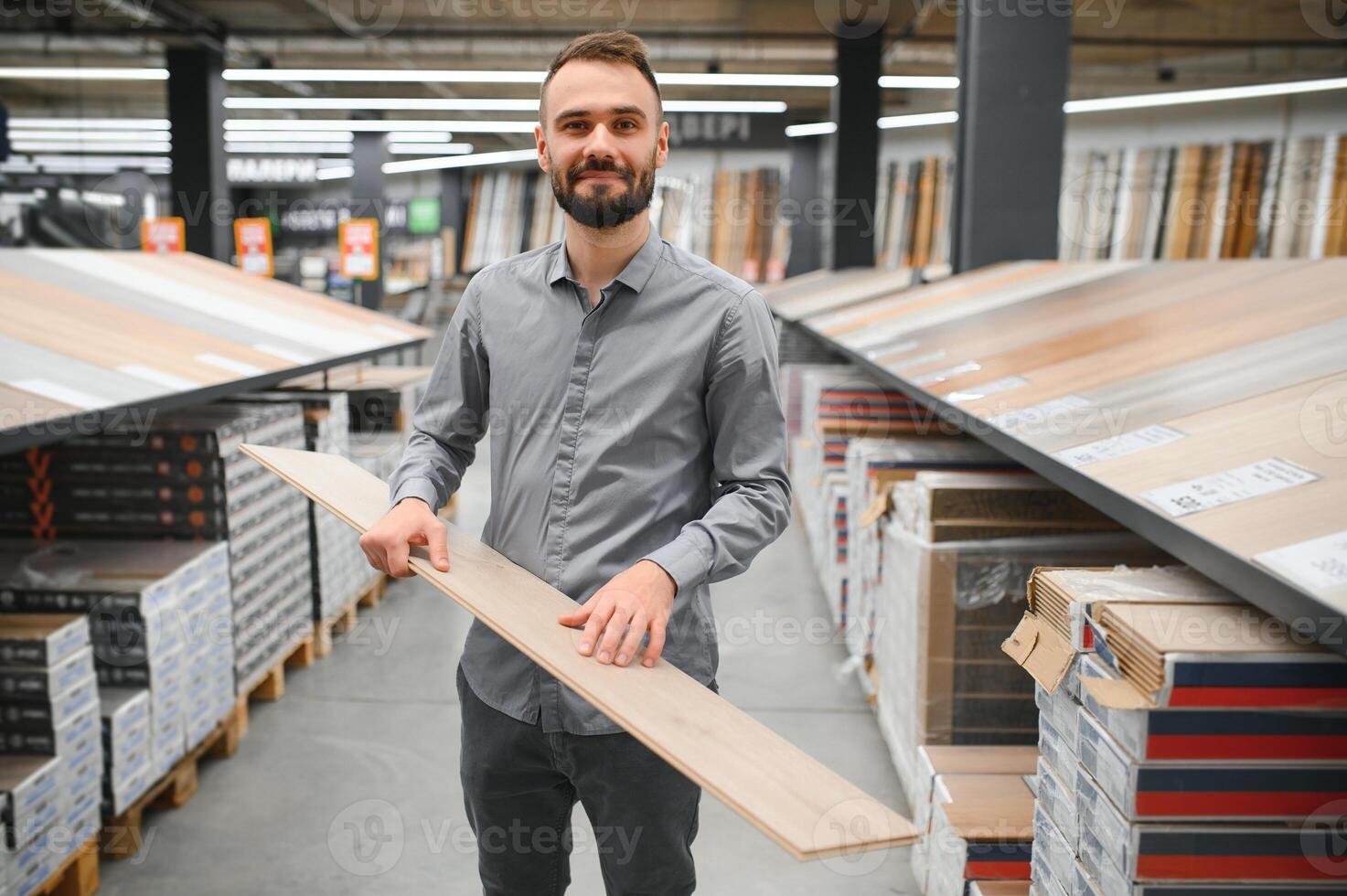 A young man chooses laminate flooring in the hardware store photo