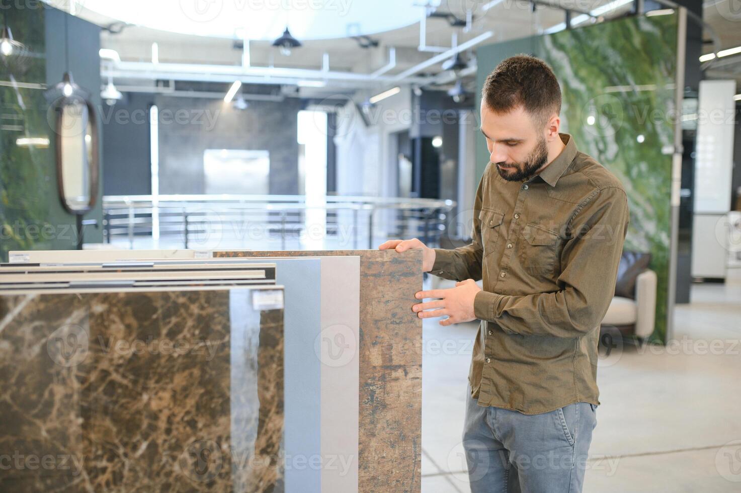 Handsome man customer choosing ceramic tile at building materials store photo