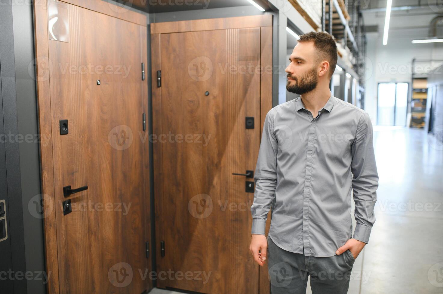 A young man chooses metal front door in the hardware store photo