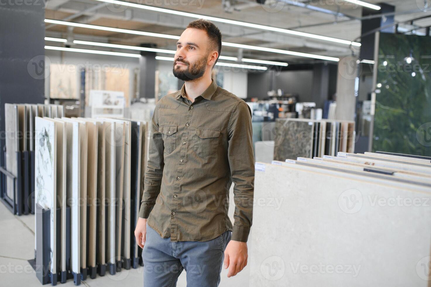 Handsome man customer choosing ceramic tile at building materials store photo