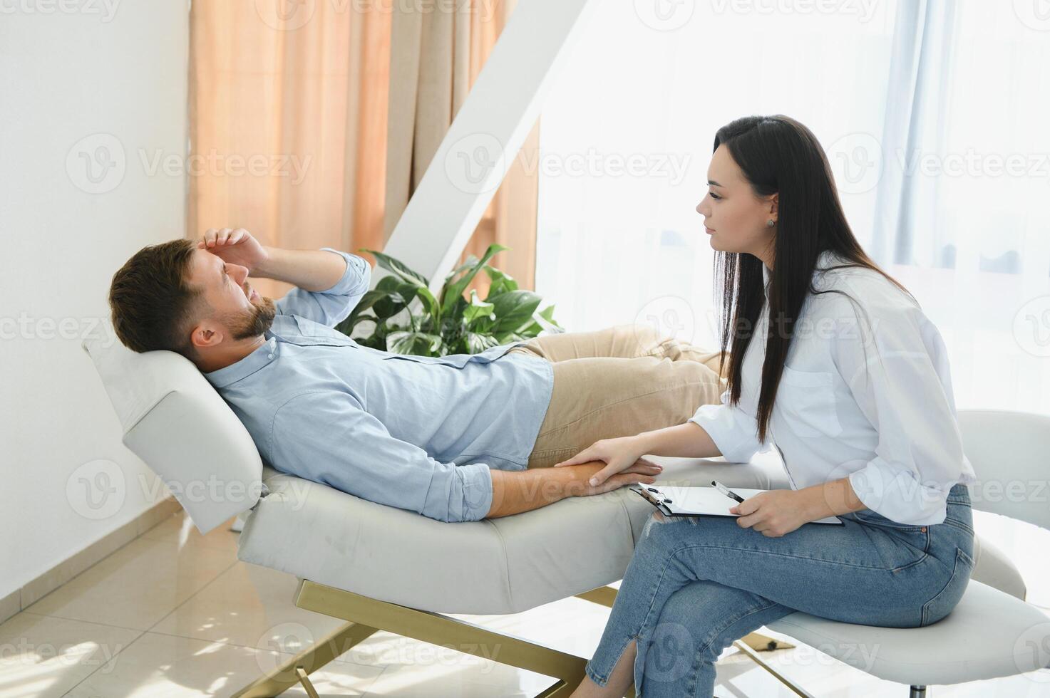 Depressed man speaking to a therapist while she is taking notes photo