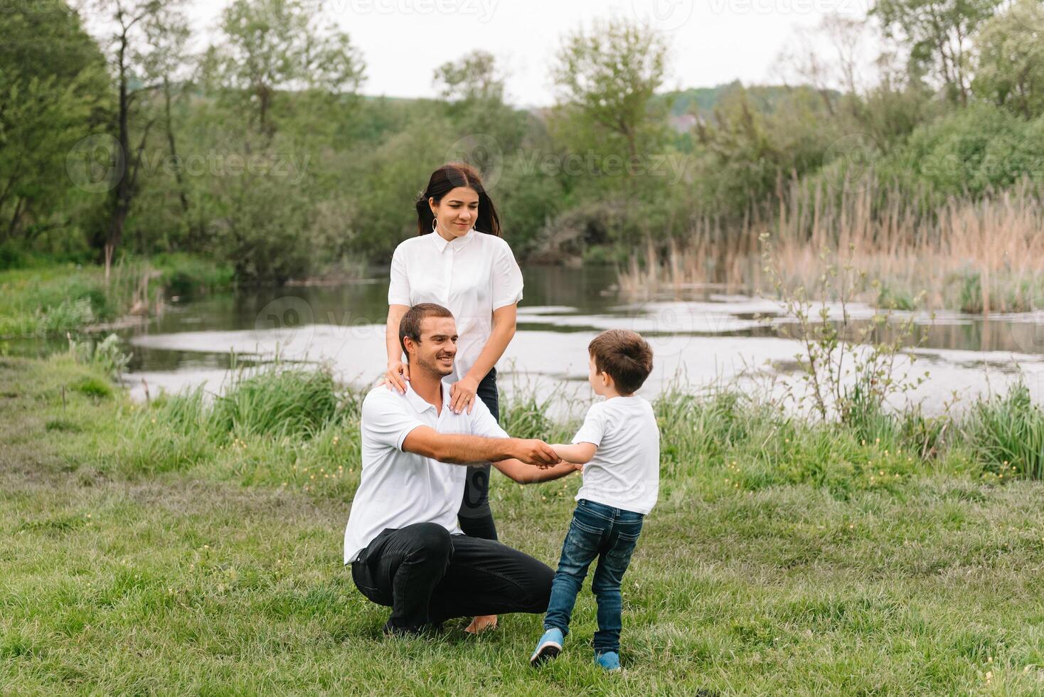 contento familia madre padre y niño hijo en naturaleza en puesta de sol. mamá, papá y niño riendo y abrazando, disfrutando naturaleza afuera. soleado día, bueno humor. concepto de un contento familia. foto