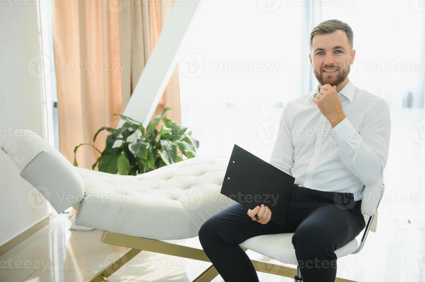 simpático medio oriental masculino psicólogo sonriente a cámara durante terapia sesión, trabajando en clínica, gratis espacio. contento psicoterapeuta posando a oficina. foto