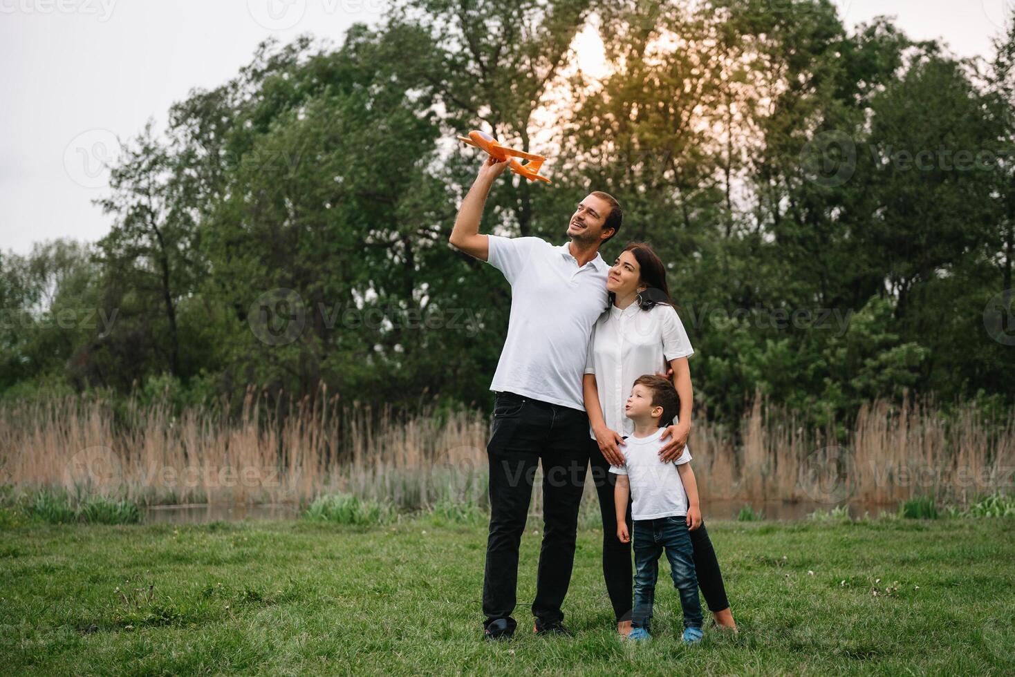 contento familia madre padre y niño hijo en naturaleza en puesta de sol. mamá, papá y niño riendo y abrazando, disfrutando naturaleza afuera. soleado día, bueno humor. concepto de un contento familia. foto