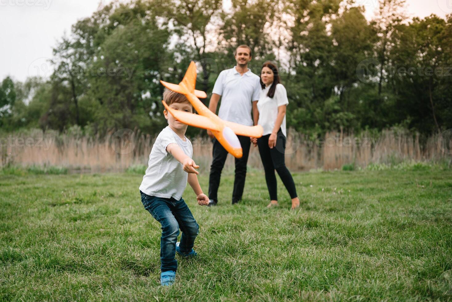 Father, mother and son playing with toy airplane in the park. friendly family. People having fun outdoors. Picture made on the background of the park and blue sky. concept of a happy family photo