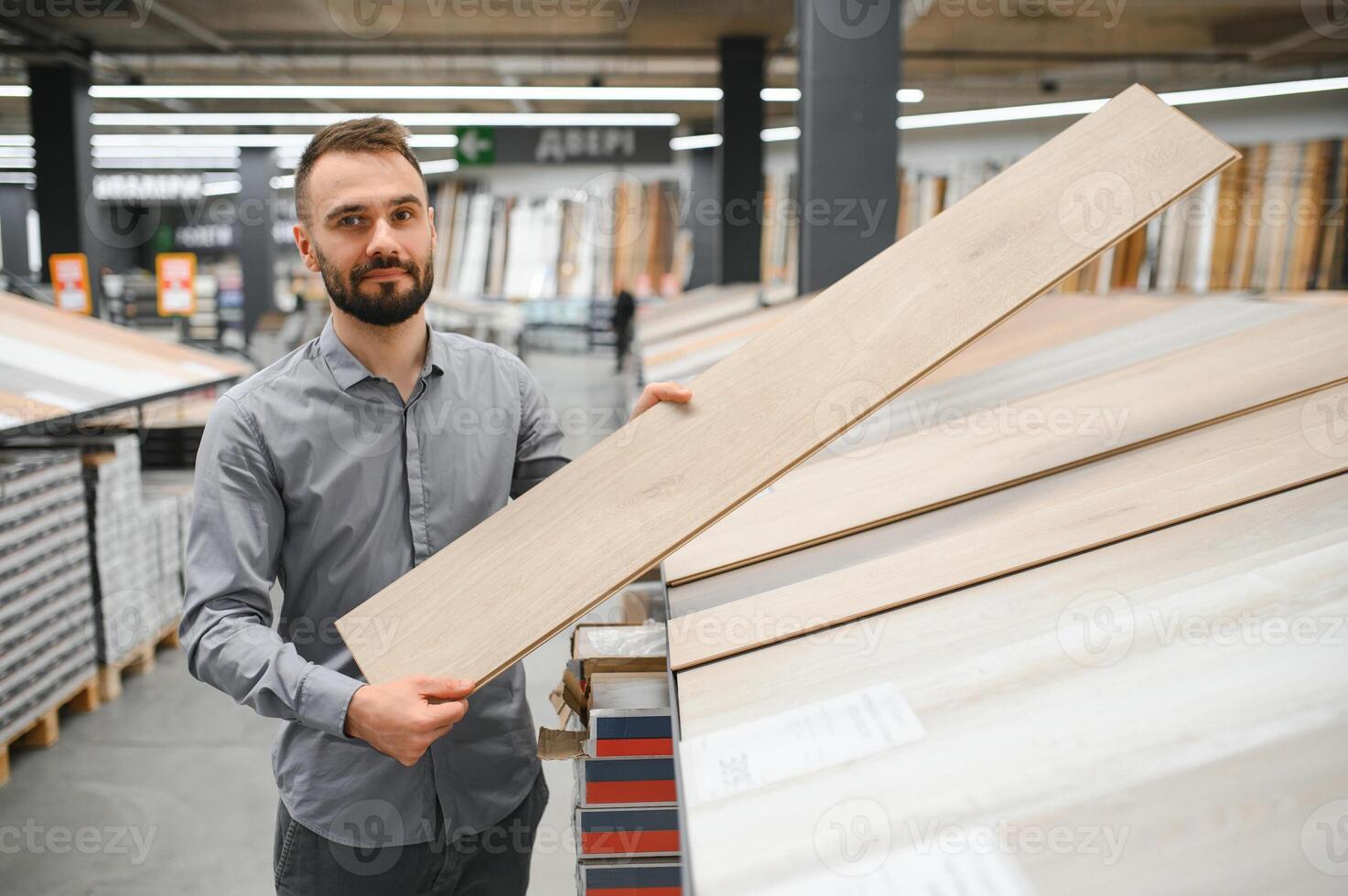 A male salesman-consultant in a hardware store sells laminate photo