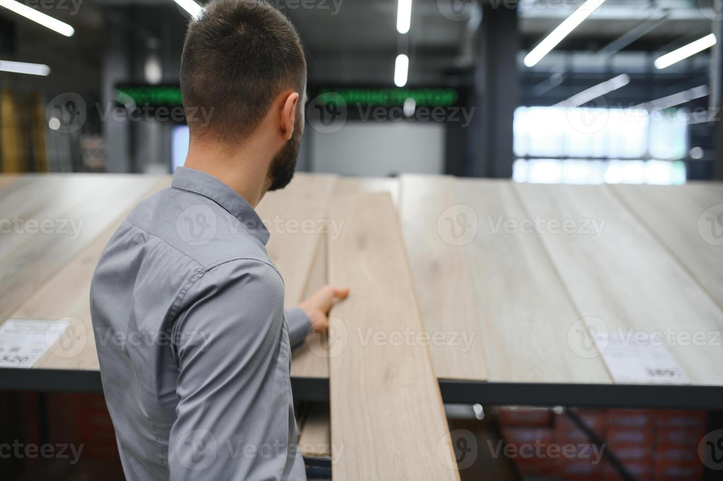 A young man chooses laminate flooring in the hardware store photo