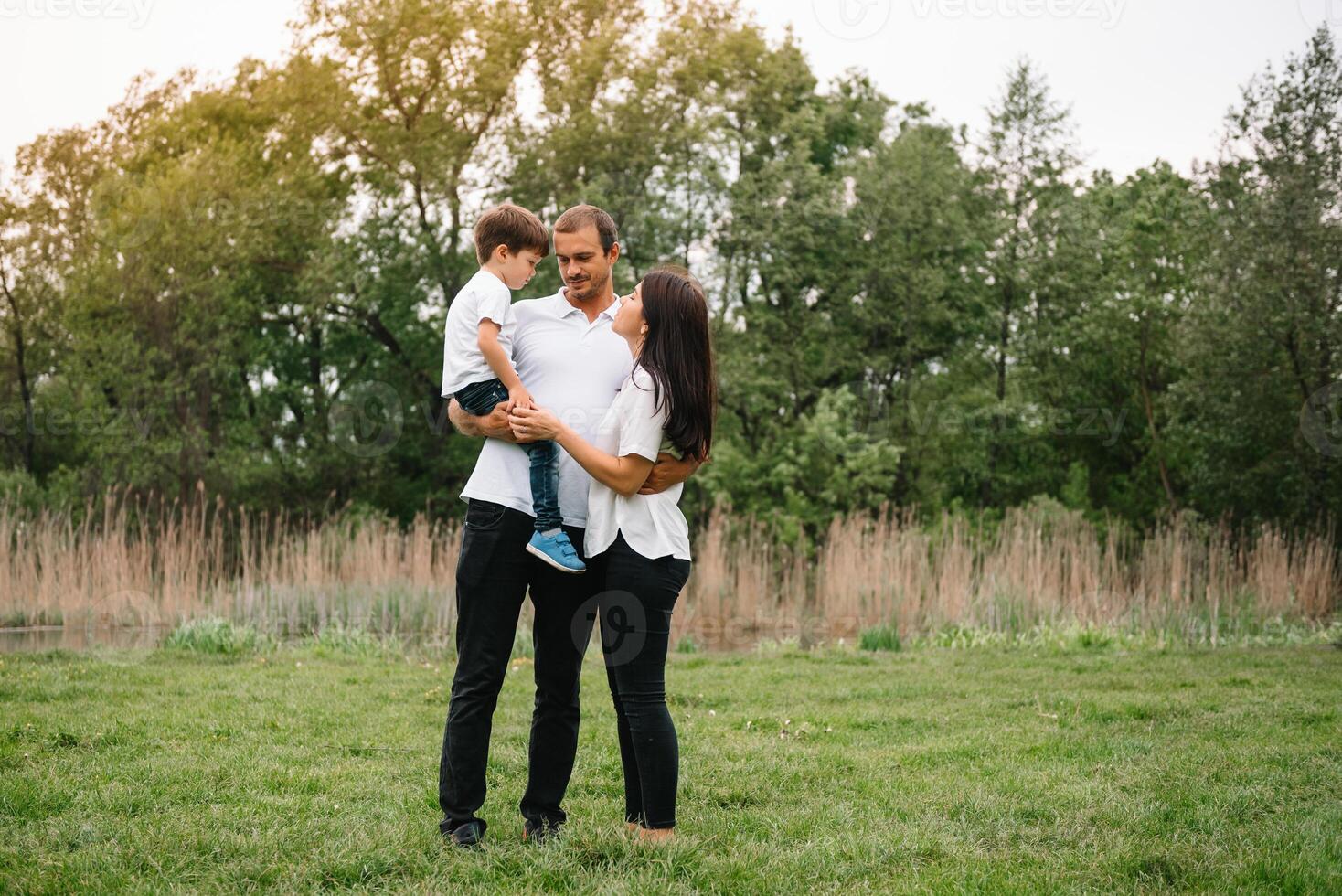 Happy family mother father and child son on nature on sunset. Mom, Dad and kid laughing and hugging, enjoying nature outside. Sunny day, good mood. concept of a happy family photo