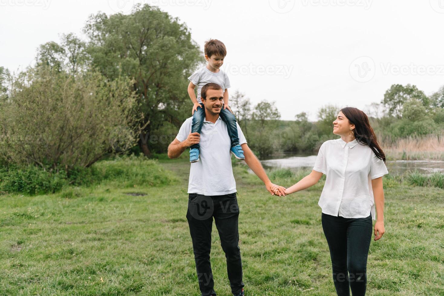 contento familia madre padre y niño hijo en naturaleza en puesta de sol. mamá, papá y niño riendo y abrazando, disfrutando naturaleza afuera. soleado día, bueno humor. concepto de un contento familia. foto