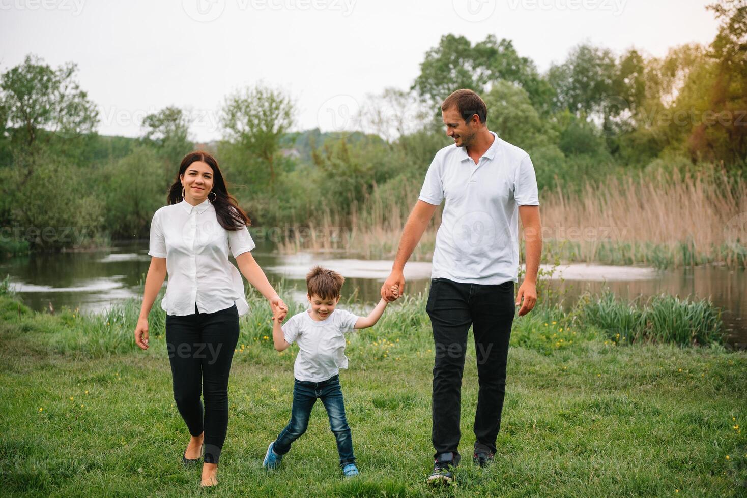 Happy family mother father and child son on nature on sunset. Mom, Dad and kid laughing and hugging, enjoying nature outside. Sunny day, good mood. concept of a happy family photo