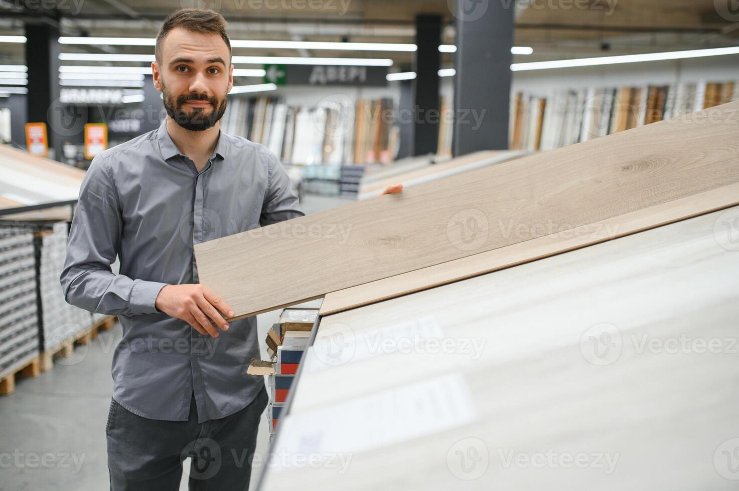 A male salesman-consultant in a hardware store sells laminate photo