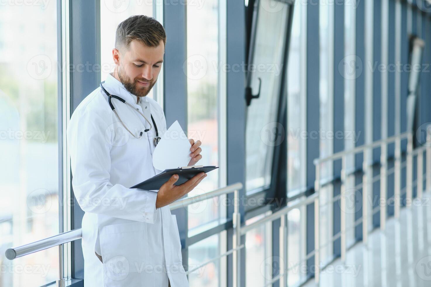 Portrait of handsome young doctor on hospital corridor photo