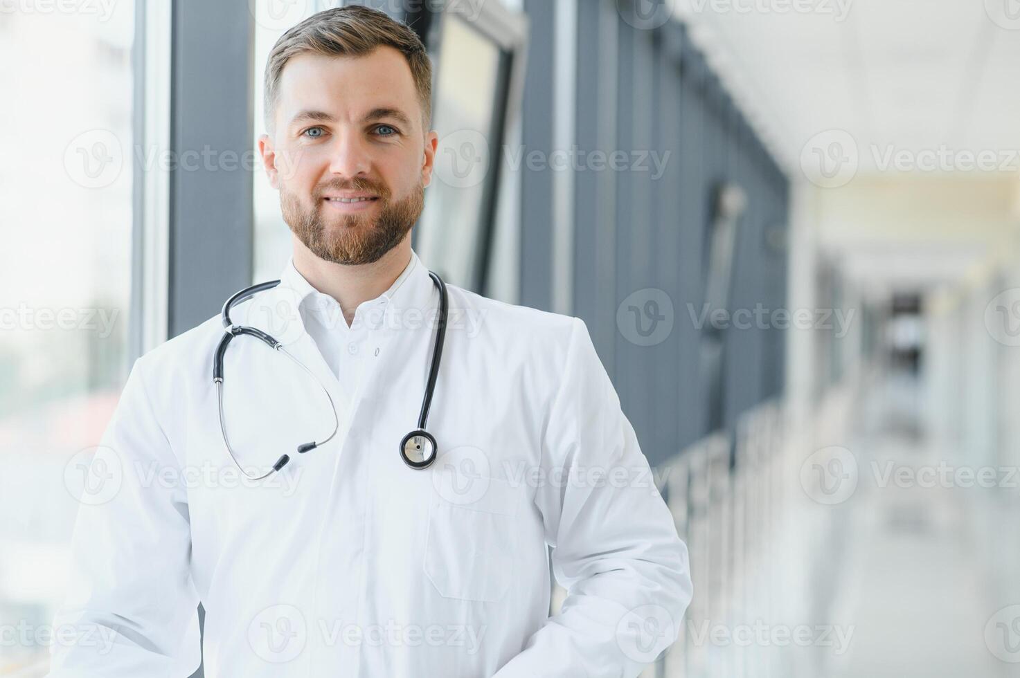 Portrait of handsome young doctor on hospital corridor photo