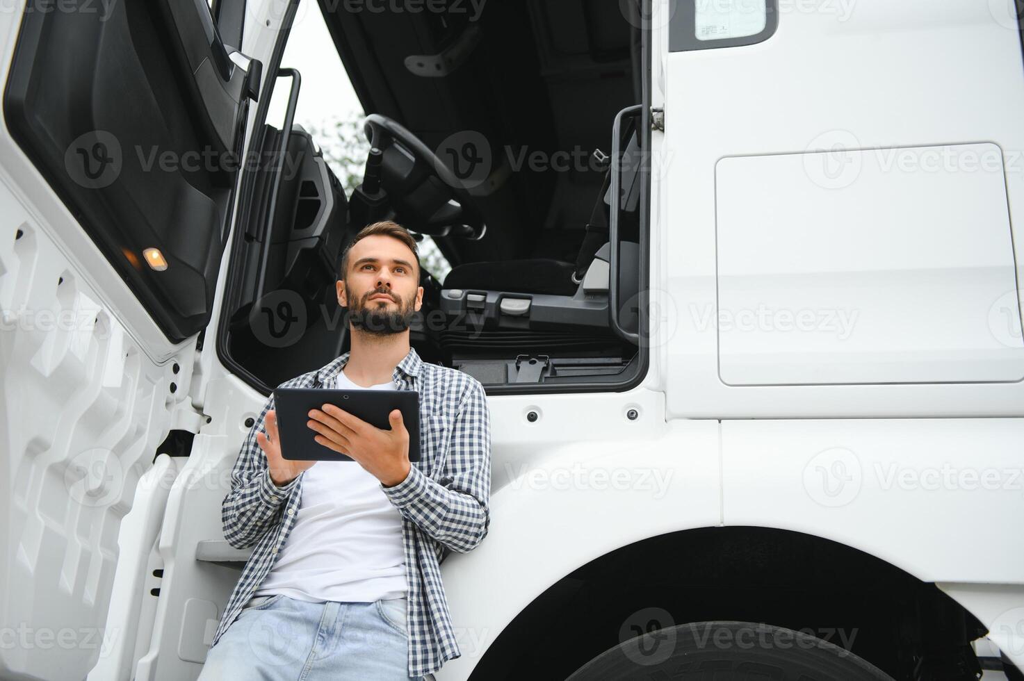 joven hermoso camión conductor es en pie con un tableta cerca el camión foto