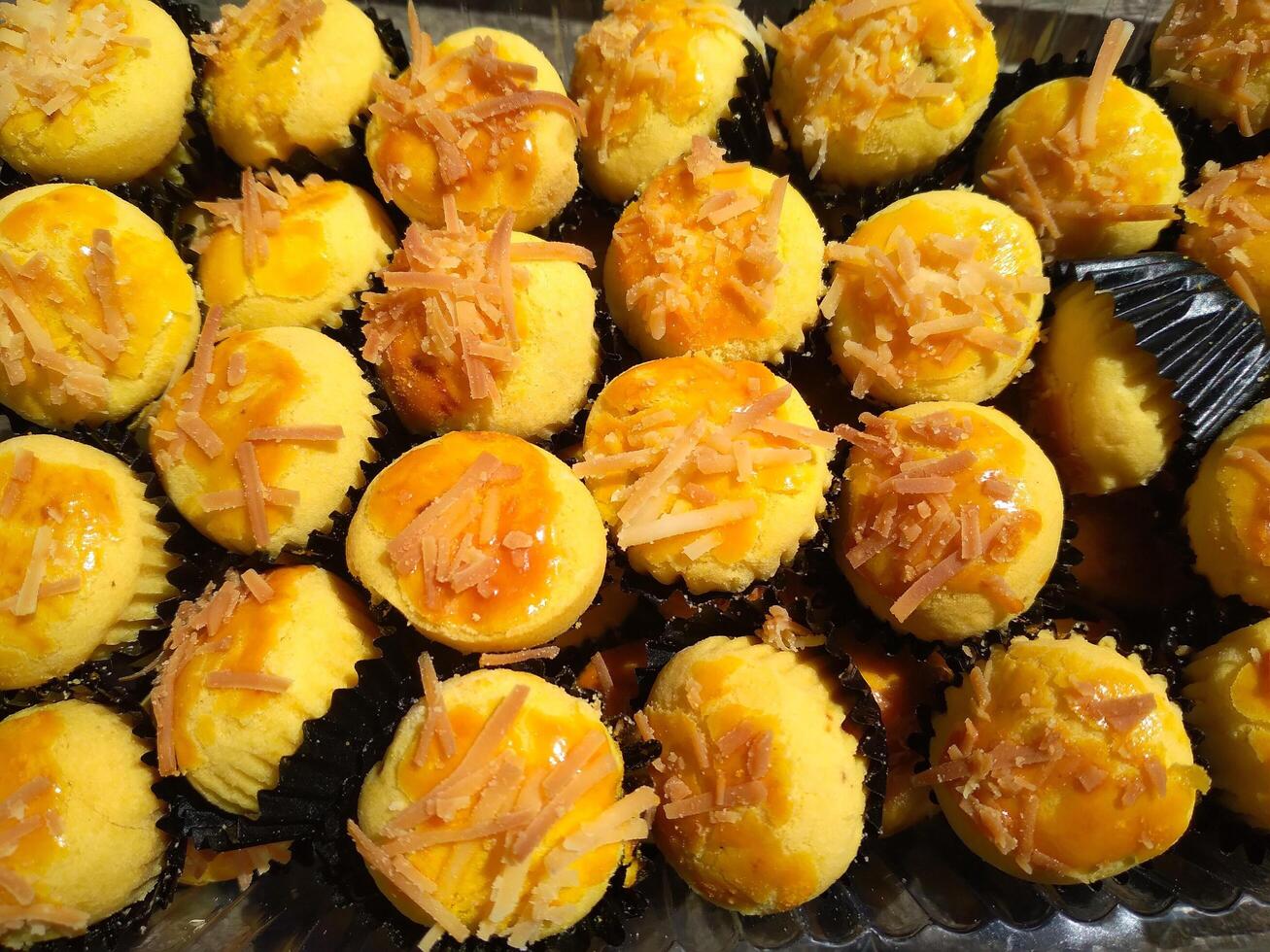 cerca arriba de nastar galletas o piña tarta forrado arriba pulcramente en negro magdalena papel. foto