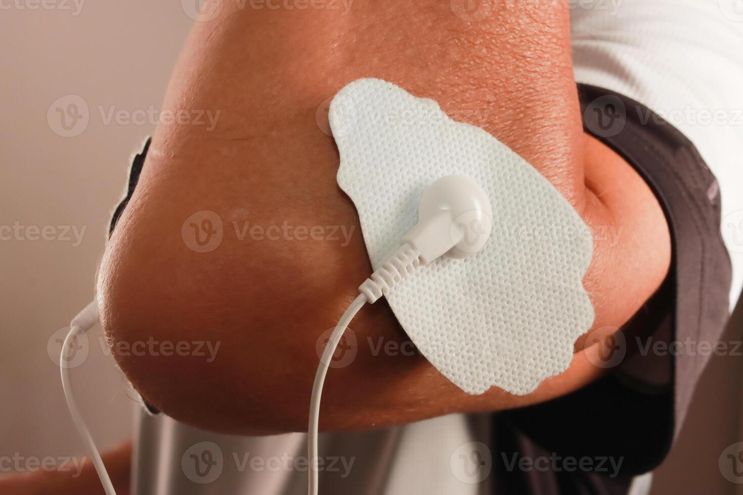Man using an Electro Therapy Massager or Tens Unit on his elbow for pain relief of Muscles and Joint photo