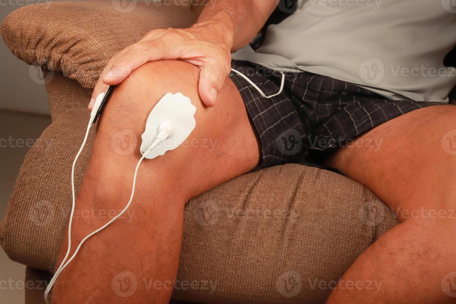 Man using an Electro Therapy Massager or Tens Unit on his knee for pain relief of Muscles and Joint photo