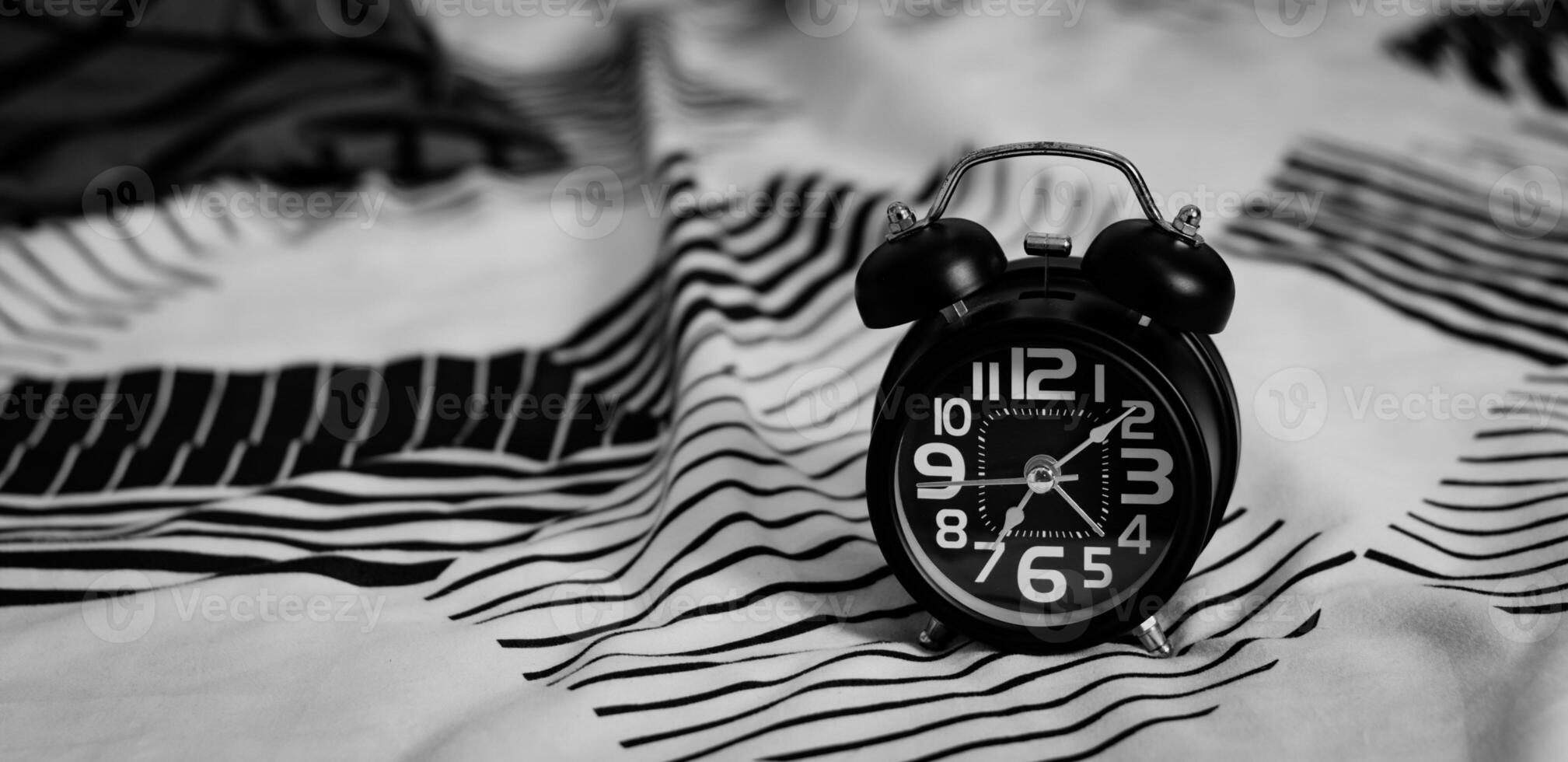 Deadline and Time management concept. Black retro alarm clock on bed. time to wake up for the morning routine photo